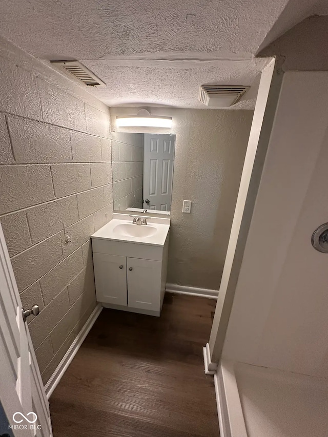 bathroom with a textured ceiling, wood finished floors, vanity, and visible vents