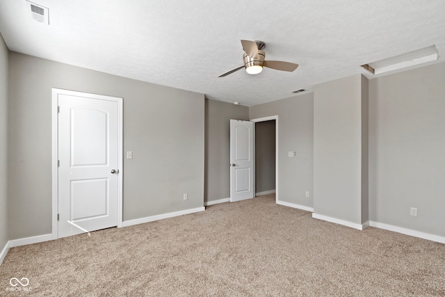 unfurnished room with a textured ceiling, visible vents, and light colored carpet