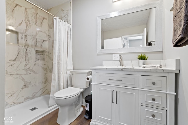 full bath with vanity, wood finished floors, a shower stall, and toilet