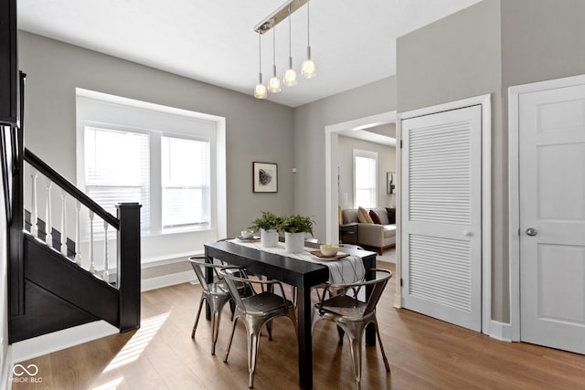 dining room featuring stairs, baseboards, and wood finished floors