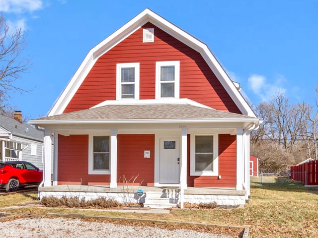 colonial inspired home with covered porch, roof with shingles, and a gambrel roof