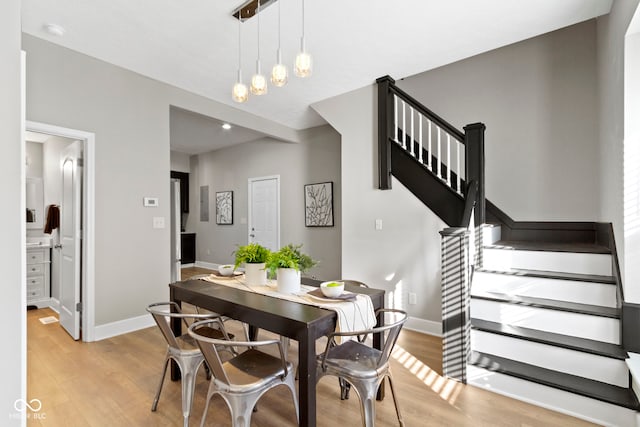 dining space with light wood-type flooring, stairway, and baseboards