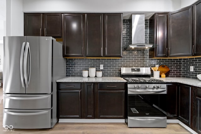 kitchen featuring stainless steel appliances, dark brown cabinetry, wall chimney range hood, and tasteful backsplash