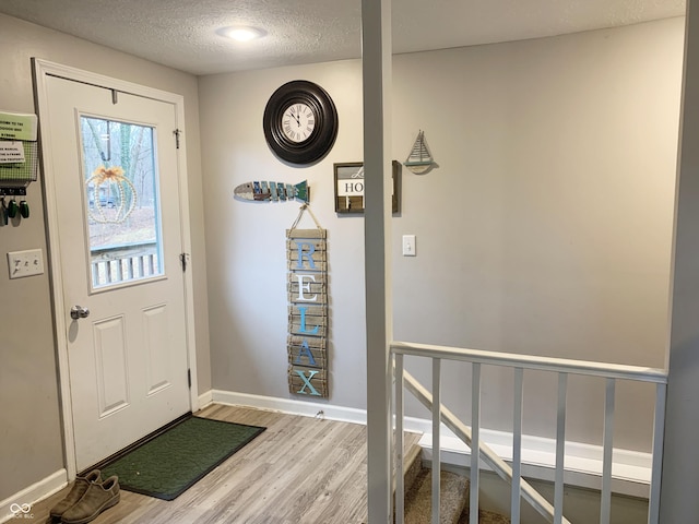 entryway featuring baseboards, a textured ceiling, and wood finished floors