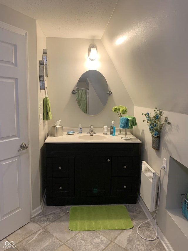 bathroom featuring a textured ceiling, vanity, and vaulted ceiling