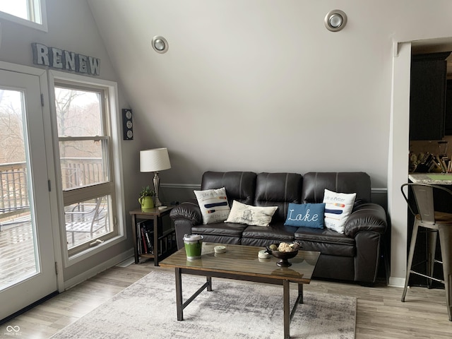 living room with baseboards, light wood-style floors, and vaulted ceiling