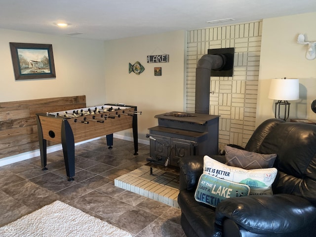 recreation room with a wood stove and baseboards