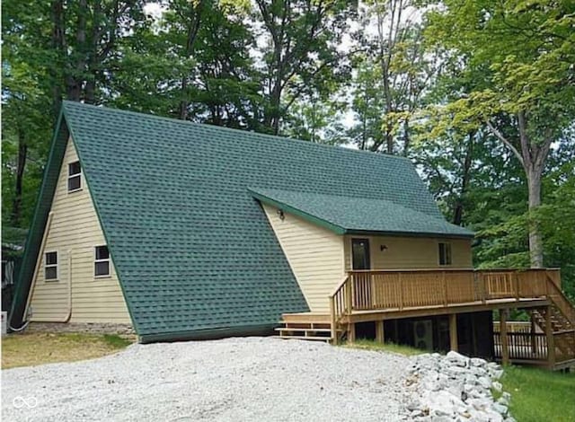 rear view of property with a wooden deck and driveway