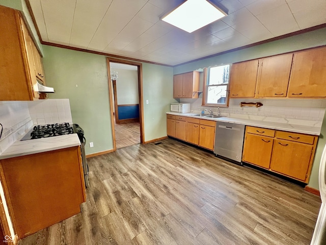 kitchen with stainless steel dishwasher, a sink, white microwave, and light wood-style floors