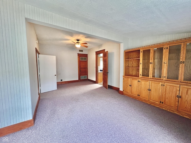 carpeted spare room with visible vents, ceiling fan, a textured ceiling, and baseboards