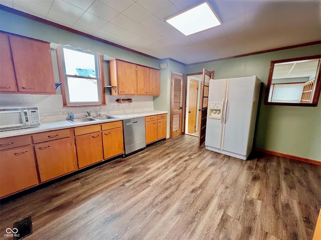 kitchen featuring light wood-type flooring, white appliances, light countertops, and a sink