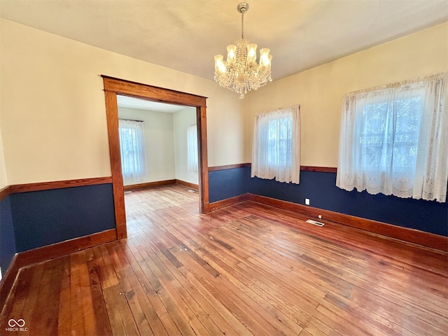 empty room featuring baseboards, a healthy amount of sunlight, visible vents, and hardwood / wood-style floors