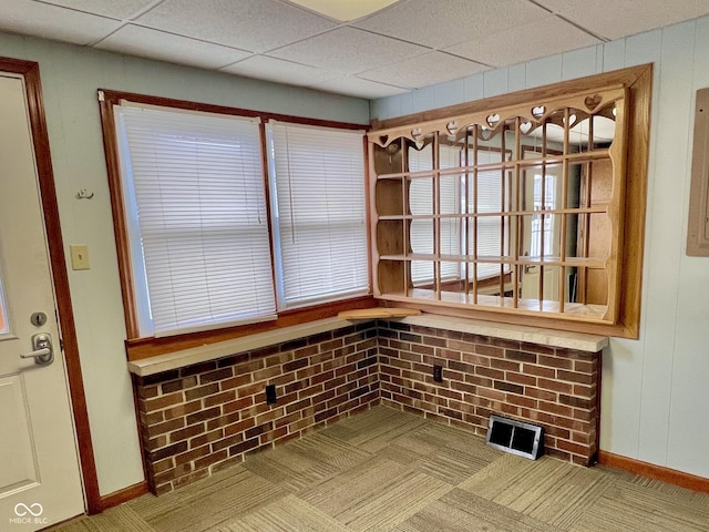 interior space with wood walls, a drop ceiling, and visible vents