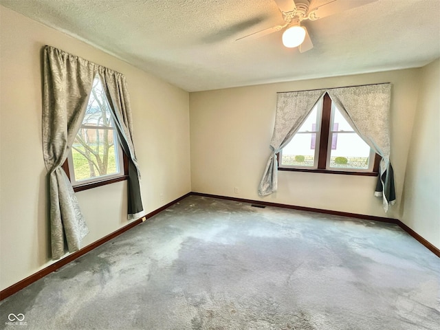 carpeted spare room featuring ceiling fan, baseboards, and a textured ceiling