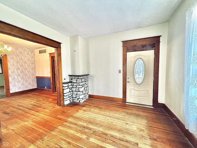 entrance foyer featuring wallpapered walls, wood-type flooring, visible vents, and baseboards