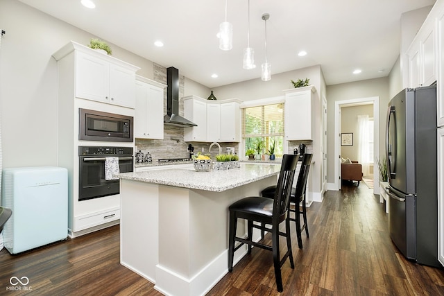 kitchen featuring oven, wall chimney range hood, built in microwave, freestanding refrigerator, and white cabinetry