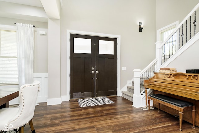 foyer with stairs, wood finished floors, and wainscoting