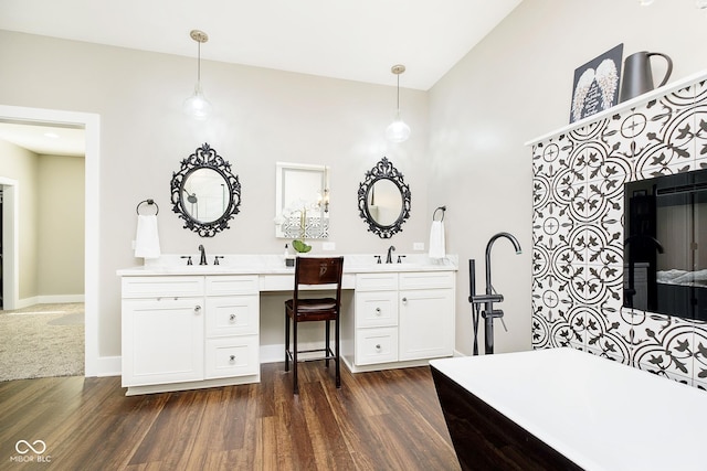 full bath with two vanities, wood finished floors, baseboards, and a sink