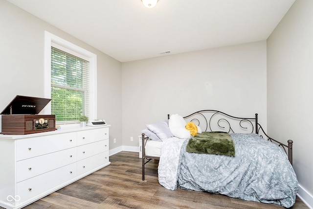 bedroom featuring visible vents, baseboards, and wood finished floors