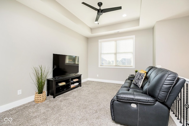 living room with a tray ceiling, baseboards, carpet floors, and ceiling fan