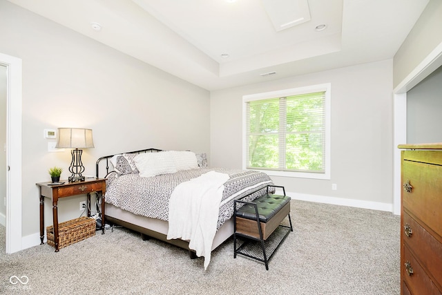 carpeted bedroom featuring a raised ceiling and baseboards