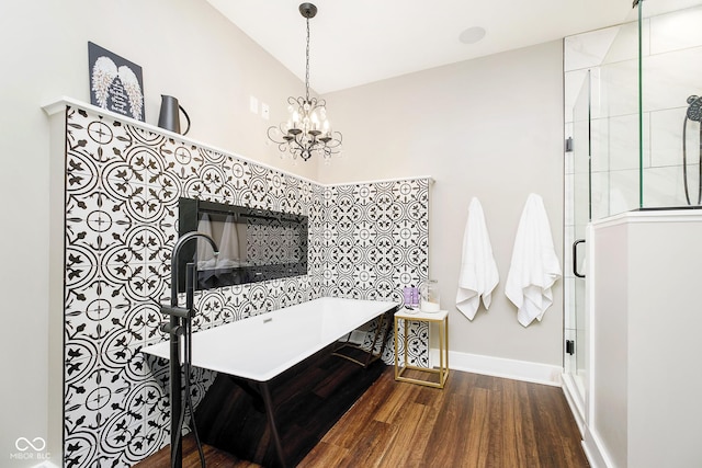 full bathroom with a shower stall, baseboards, a tub to relax in, wood finished floors, and a notable chandelier