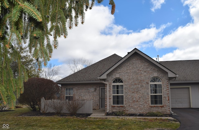 single story home featuring aphalt driveway, brick siding, an attached garage, and roof with shingles