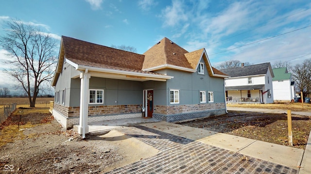 view of front of property with brick siding, a shingled roof, and stucco siding