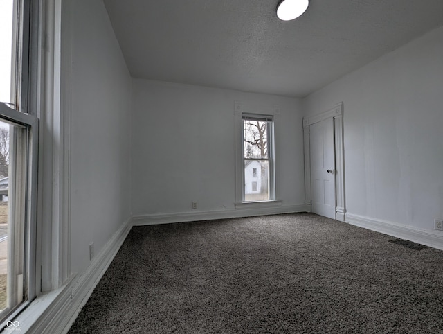 empty room featuring a textured ceiling, carpet floors, and baseboards