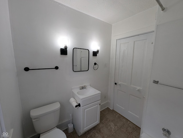 half bath featuring baseboards, a textured ceiling, toilet, and vanity