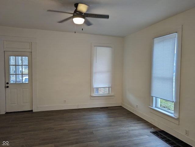 spare room with visible vents, dark wood-type flooring, a ceiling fan, and baseboards