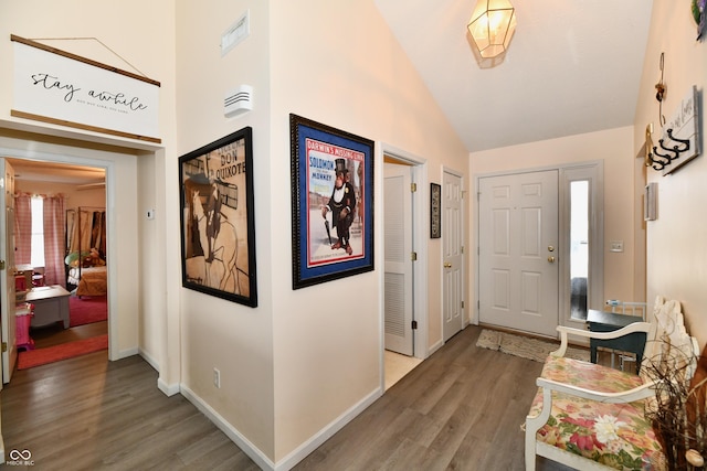 foyer featuring baseboards, visible vents, high vaulted ceiling, and wood finished floors