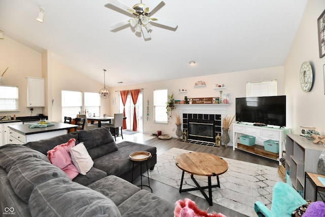 living area featuring vaulted ceiling, a fireplace, wood finished floors, and a ceiling fan