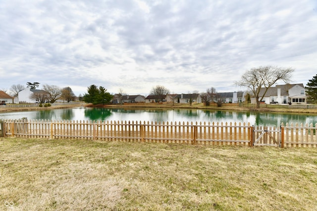 view of yard featuring a water view, fence, and a residential view