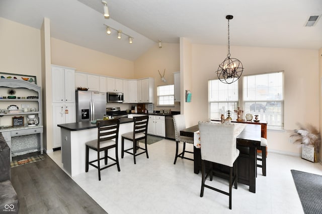 dining space with light floors, visible vents, an inviting chandelier, high vaulted ceiling, and baseboards