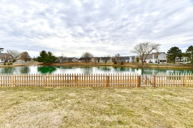 view of yard with a residential view, a water view, and fence