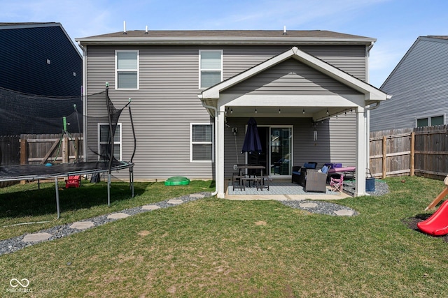 back of property with a trampoline, a yard, a patio, and a fenced backyard