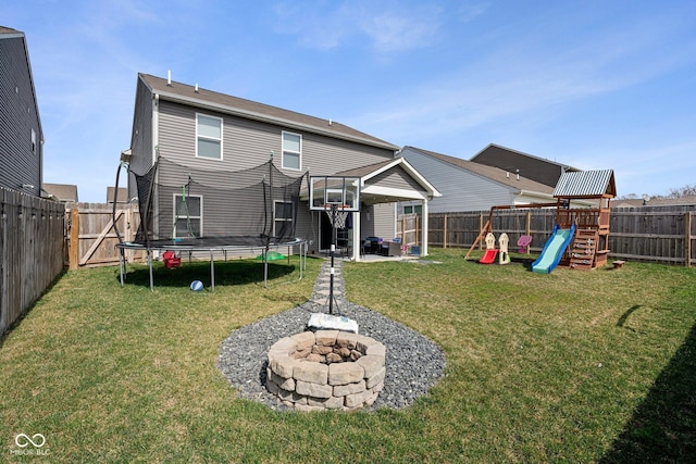 rear view of house with a trampoline, a playground, and a fenced backyard