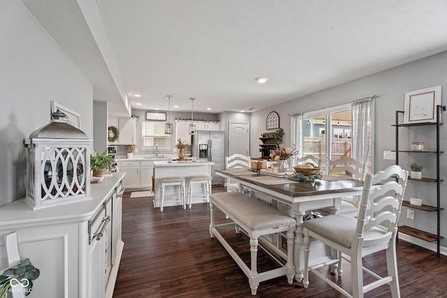 dining space with dark wood-type flooring, recessed lighting, and a textured ceiling