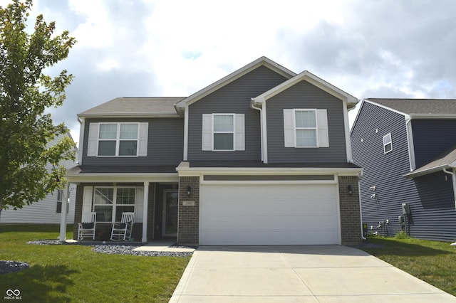 view of front of property with brick siding, covered porch, an attached garage, driveway, and a front lawn