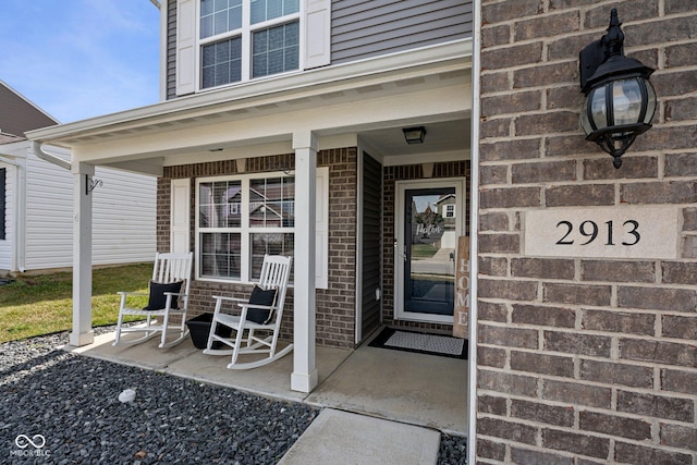 entrance to property with covered porch and brick siding