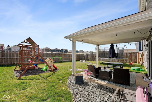 view of yard with a trampoline, a fenced backyard, a playground, and a patio