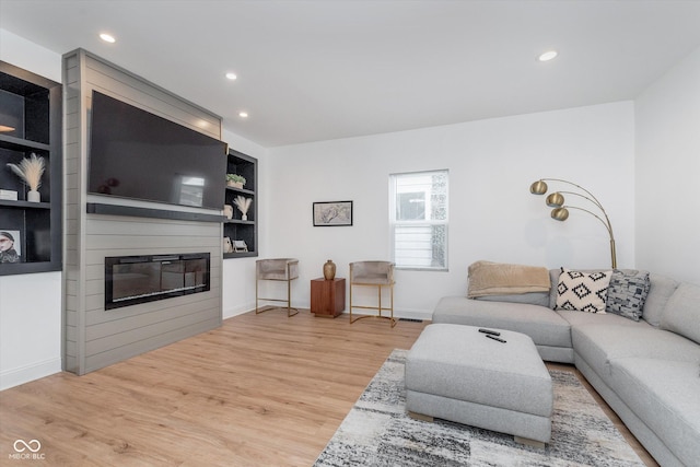 living area featuring built in shelves, a fireplace, recessed lighting, wood finished floors, and baseboards