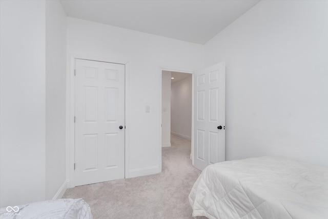 bedroom with light colored carpet and baseboards