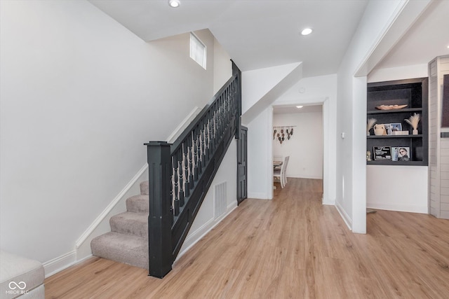 stairway with built in features, recessed lighting, visible vents, wood finished floors, and baseboards