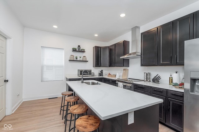 kitchen featuring open shelves, a breakfast bar, stainless steel appliances, a sink, and wall chimney exhaust hood