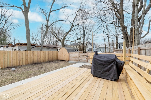 wooden deck with a fenced backyard, an outdoor structure, a grill, and a residential view