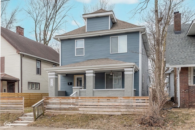 american foursquare style home with covered porch, roof with shingles, and a fenced front yard