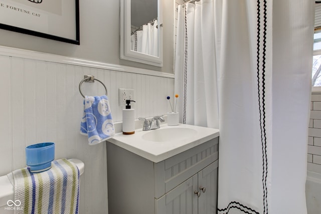 bathroom with a shower with shower curtain, wainscoting, and vanity