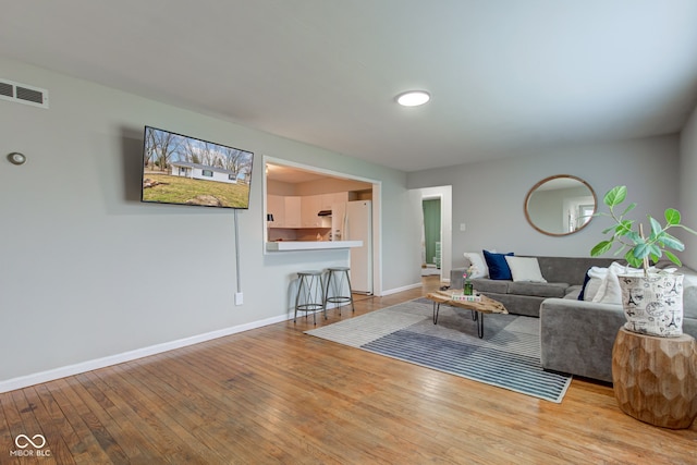 living area with hardwood / wood-style flooring, visible vents, and baseboards